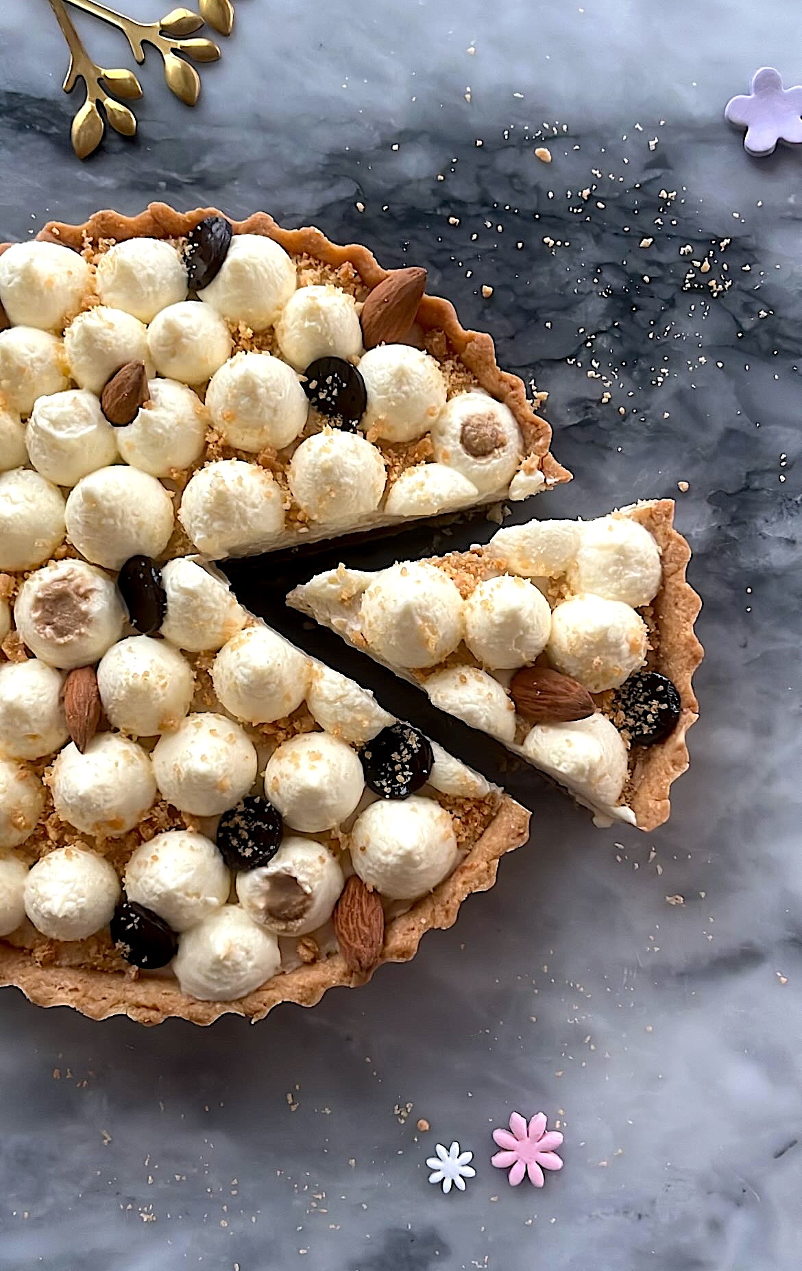 Tart topped with heart-shaped cream, decorated with almonds and pistachios.