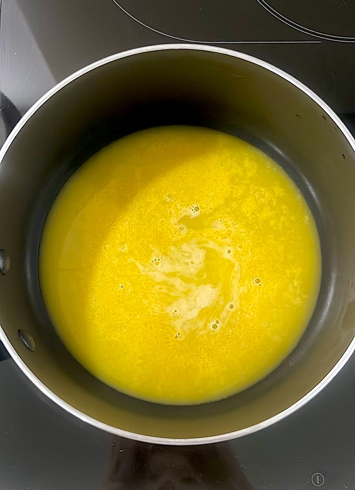 Lemon zest, juice, and sugar being heated in a saucepan