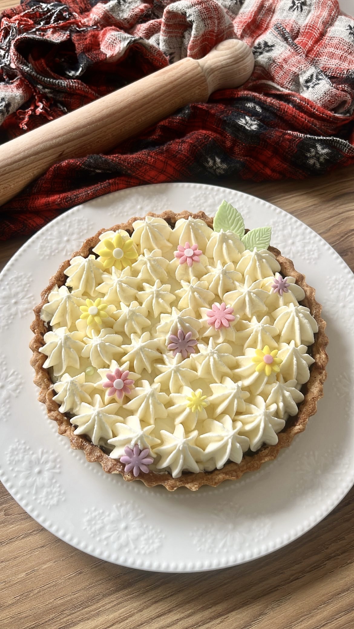 Lemon tart topped with piped cream, decorated with sugar paste.