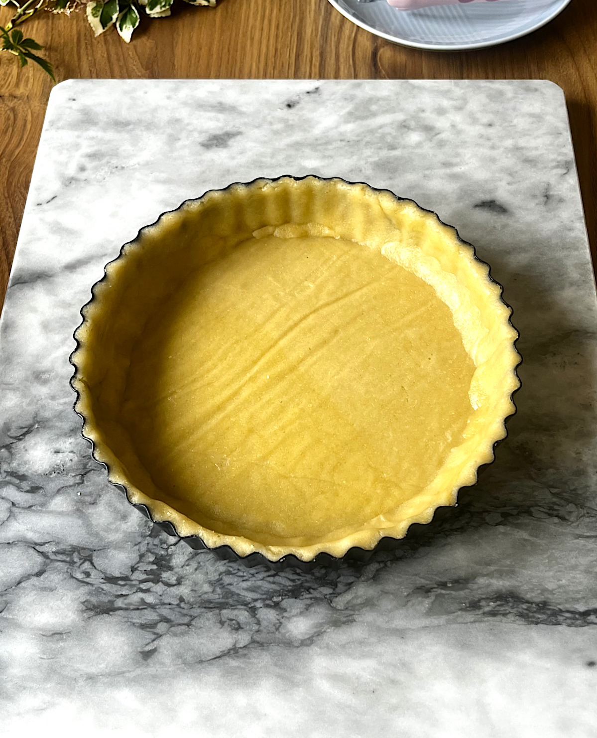 Dough pressed evenly into a buttered tart mould